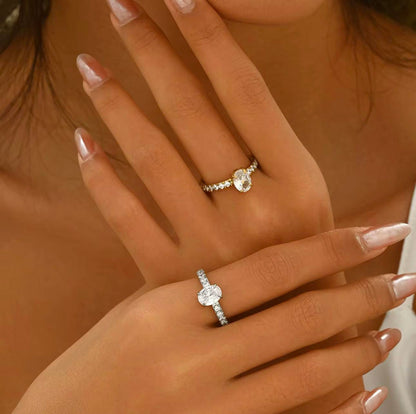 Silver ring with oval gemstone and further gemstones along the band of the ring, pictured on a hand