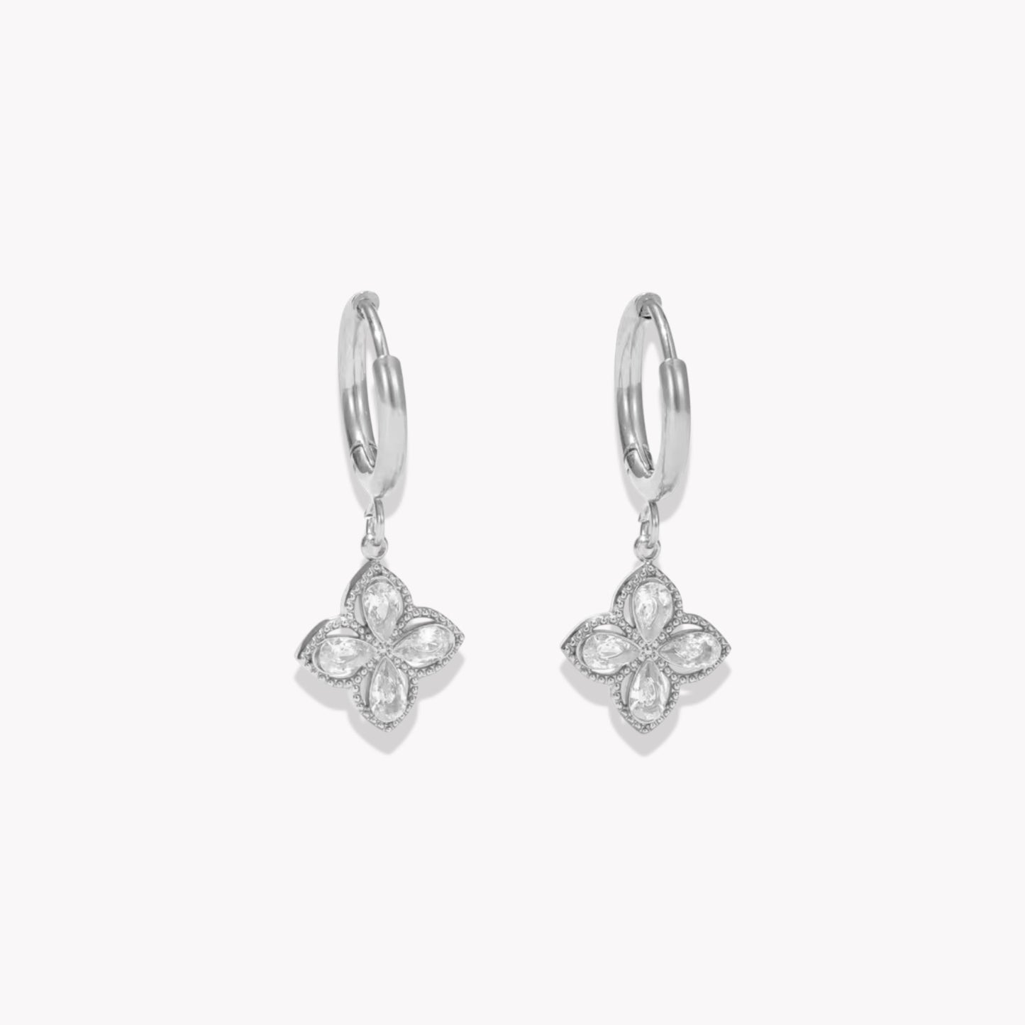Silver earrings with clear gemstone detail pictured on a light grey background