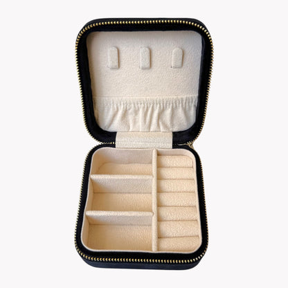 Open black jewelry case with compartments for earrings and rings on a white background