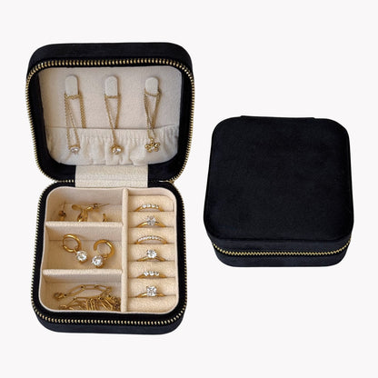 Black jewelry travel case with gold and silver jewelry inside on a white background