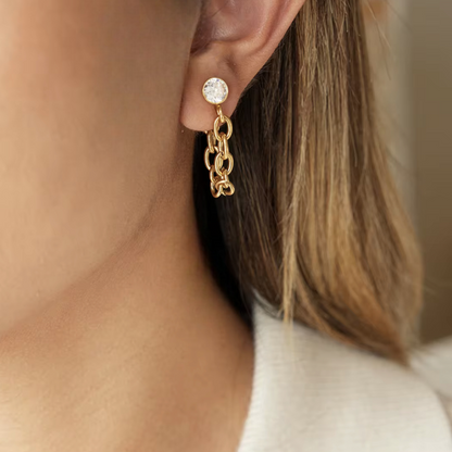 Gold earrings featuring gemstone and chain design shown being worn in an ear