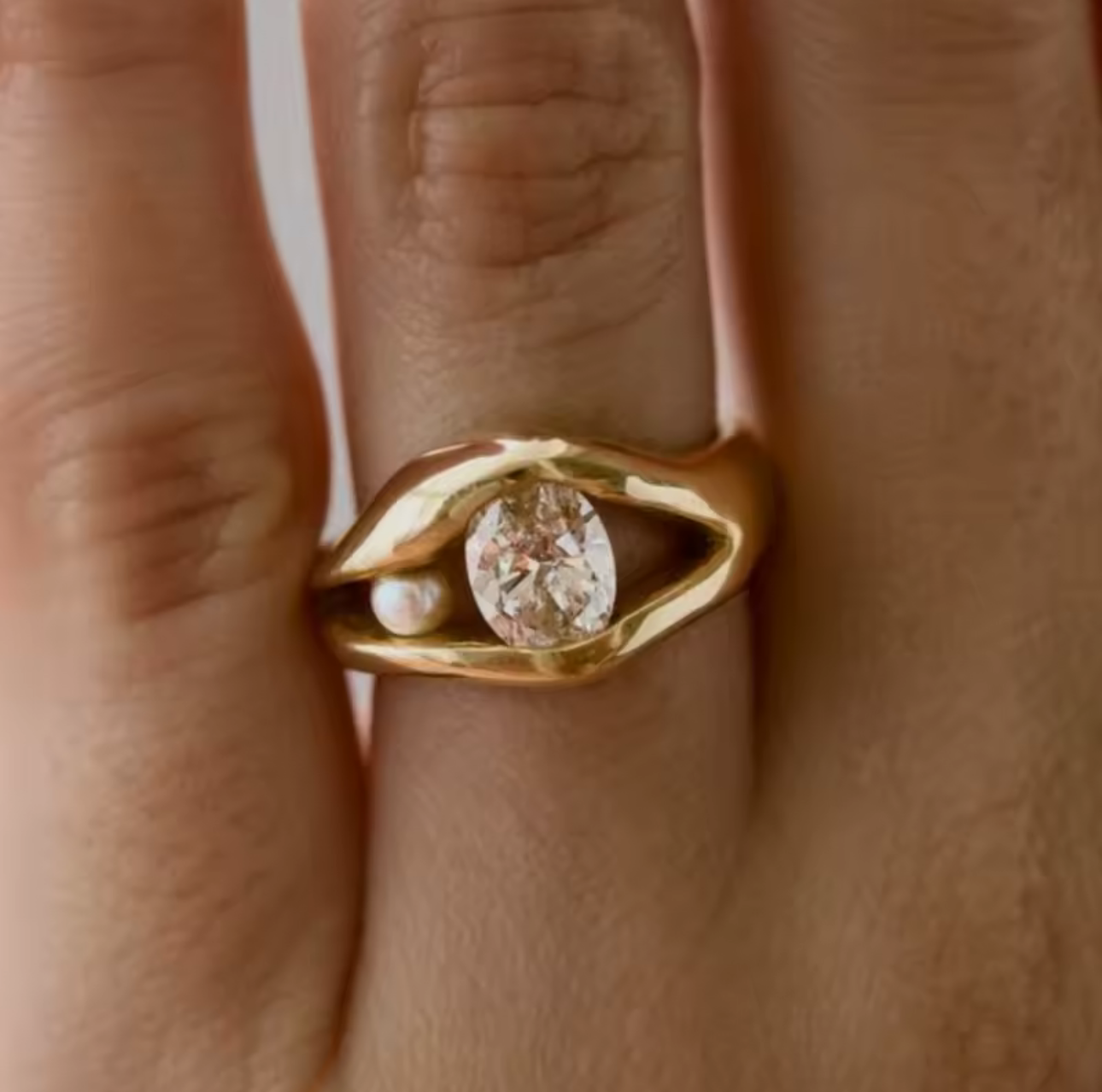 Gold ring with a diamond and pearl on a finger