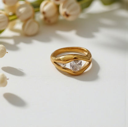 Gold ring with a diamond and pearl on a light background with flowers