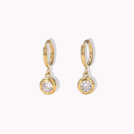 gold hooped earrings with bezel set drop gemstone pictured on a light beige background