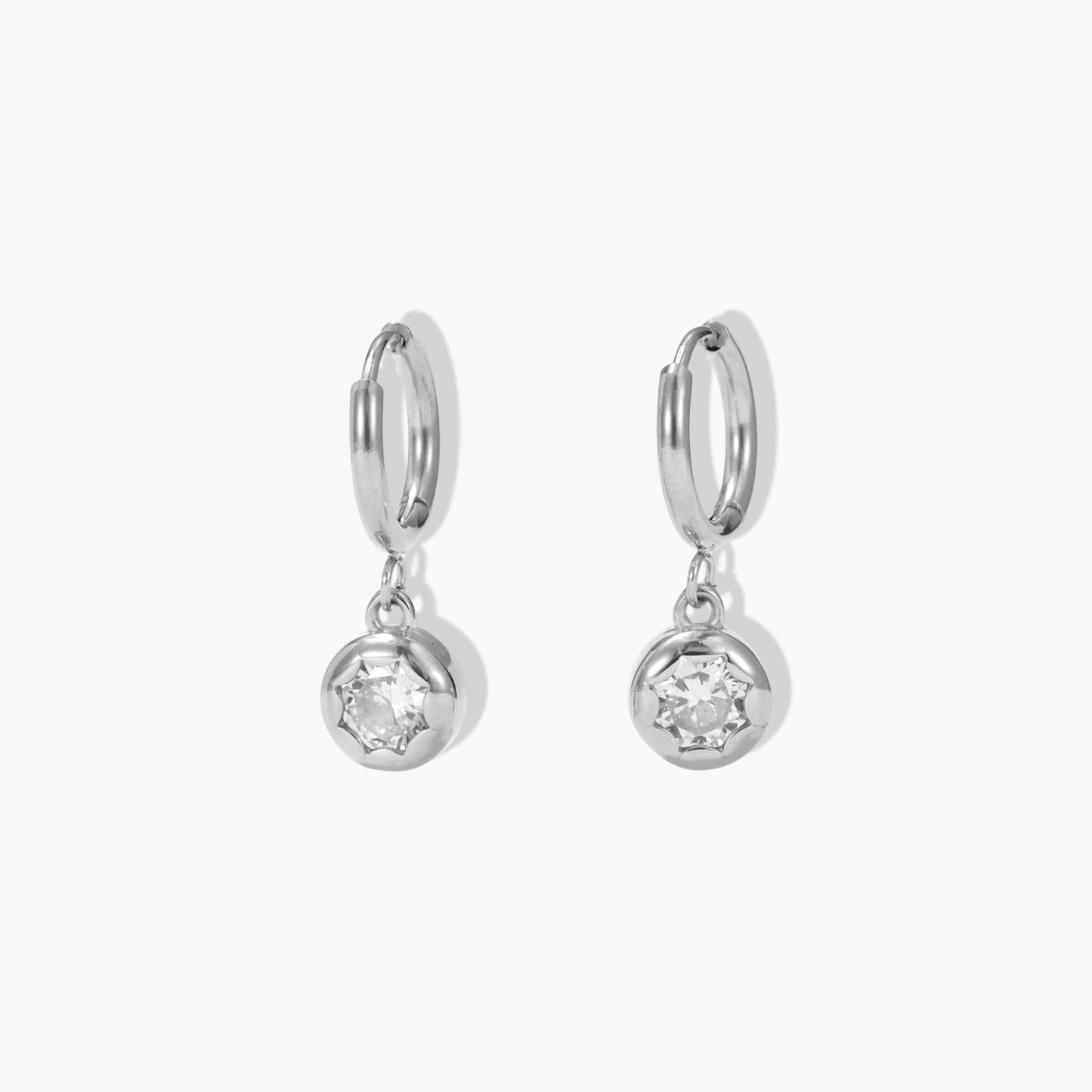 silver hooped earrings with bezel set drop gemstone pictured on a light beige background