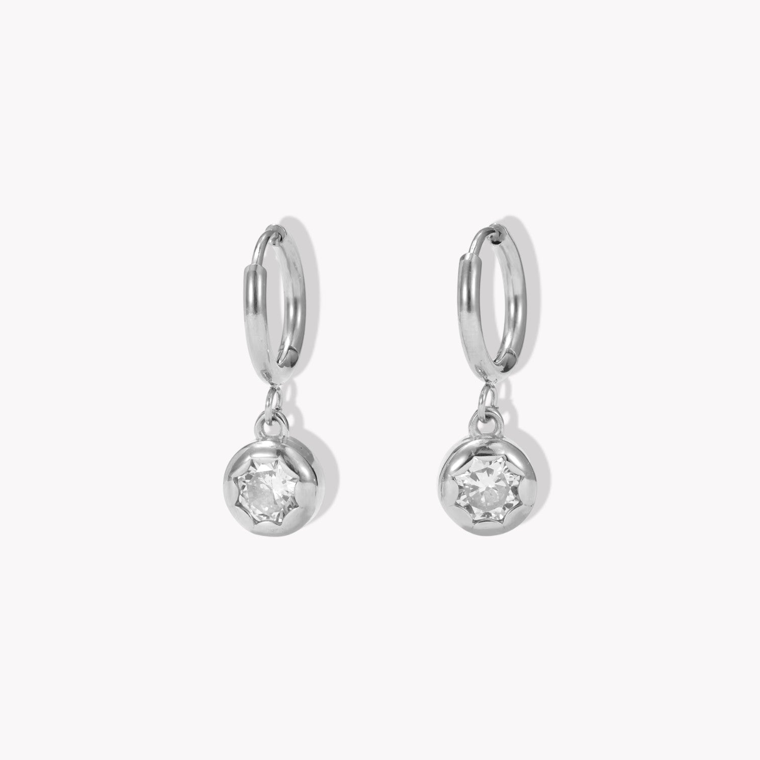 silver hooped earrings with bezel set drop gemstone pictured on a light beige background