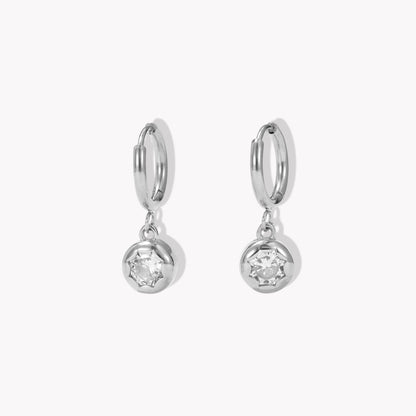 silver hooped earrings with bezel set drop gemstone pictured on a light beige background