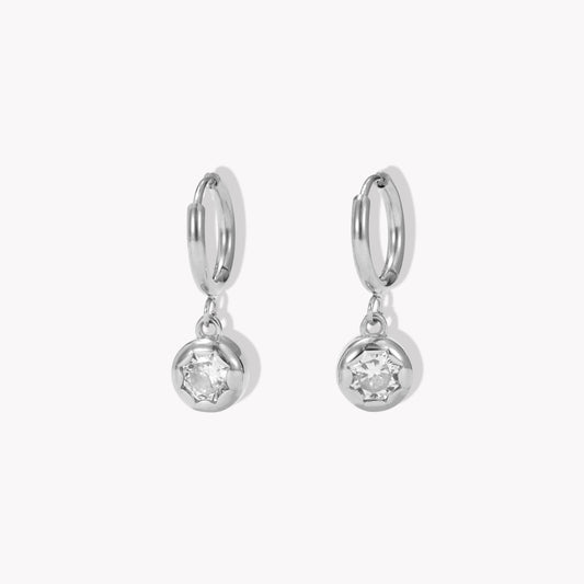 silver hooped earrings with bezel set drop gemstone pictured on a light beige background