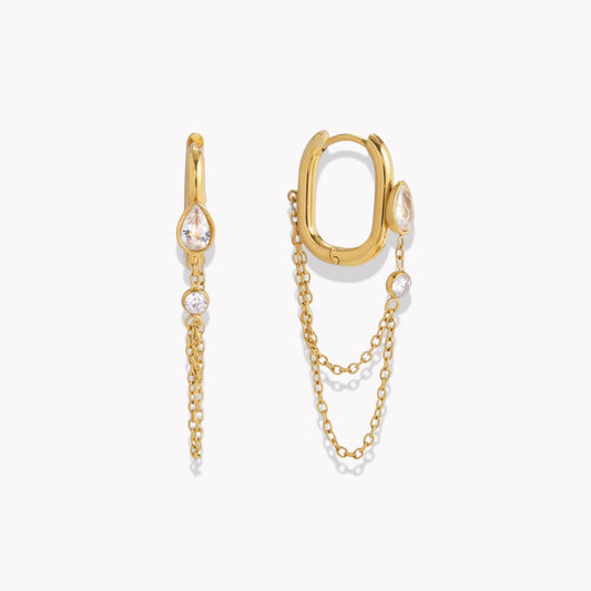 Gold hoop earrings with chain extensions andclear gemstones on a white background