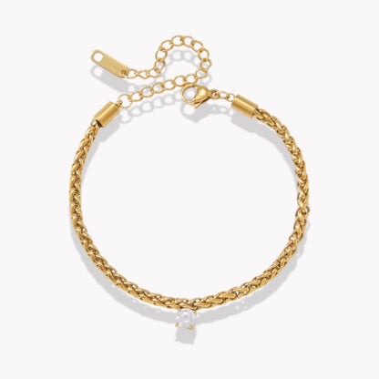 gold bracelet with a single drop gemstone pictured on a light grey background