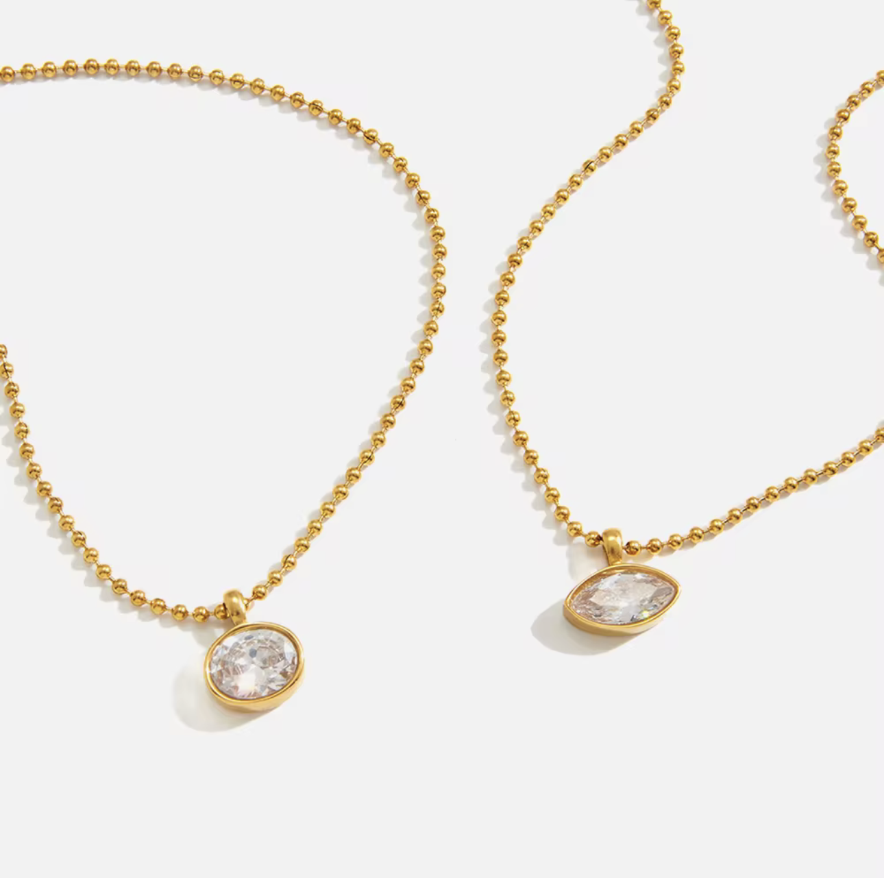 Two gold necklaces with round pendants on a white background