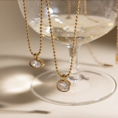 Gold necklaces with pendant stones on a glass surface