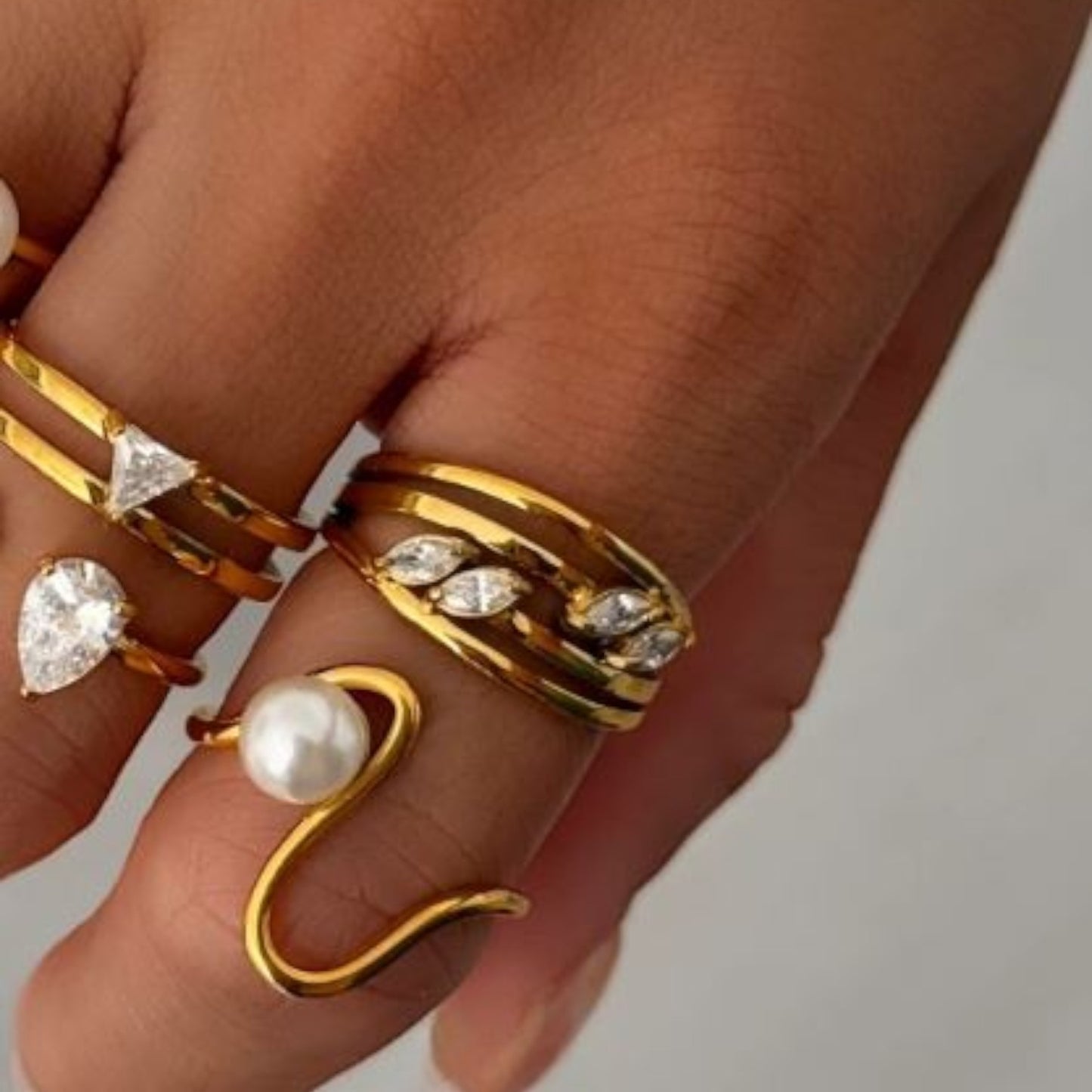Gold ring with layers of ring band and four marquise shaped stones being worn on a finger - with other rings