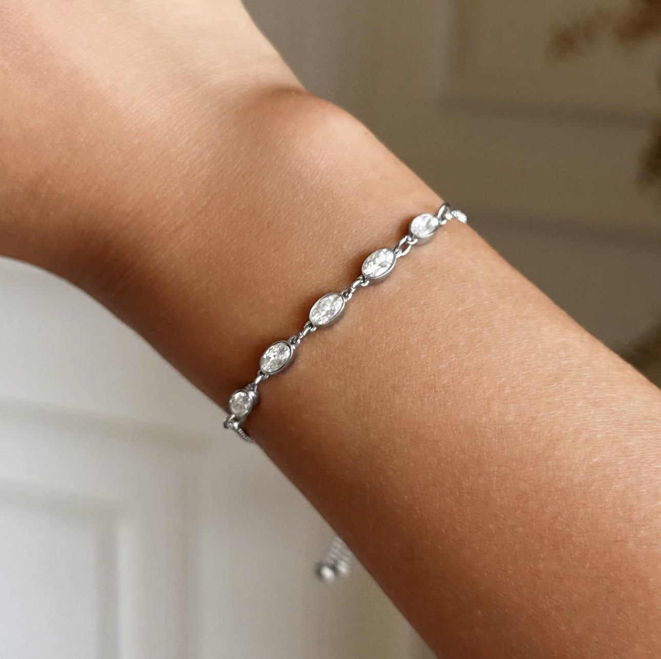 Silver bracelet on a wrist with five oval shape gemstones and a blurred background