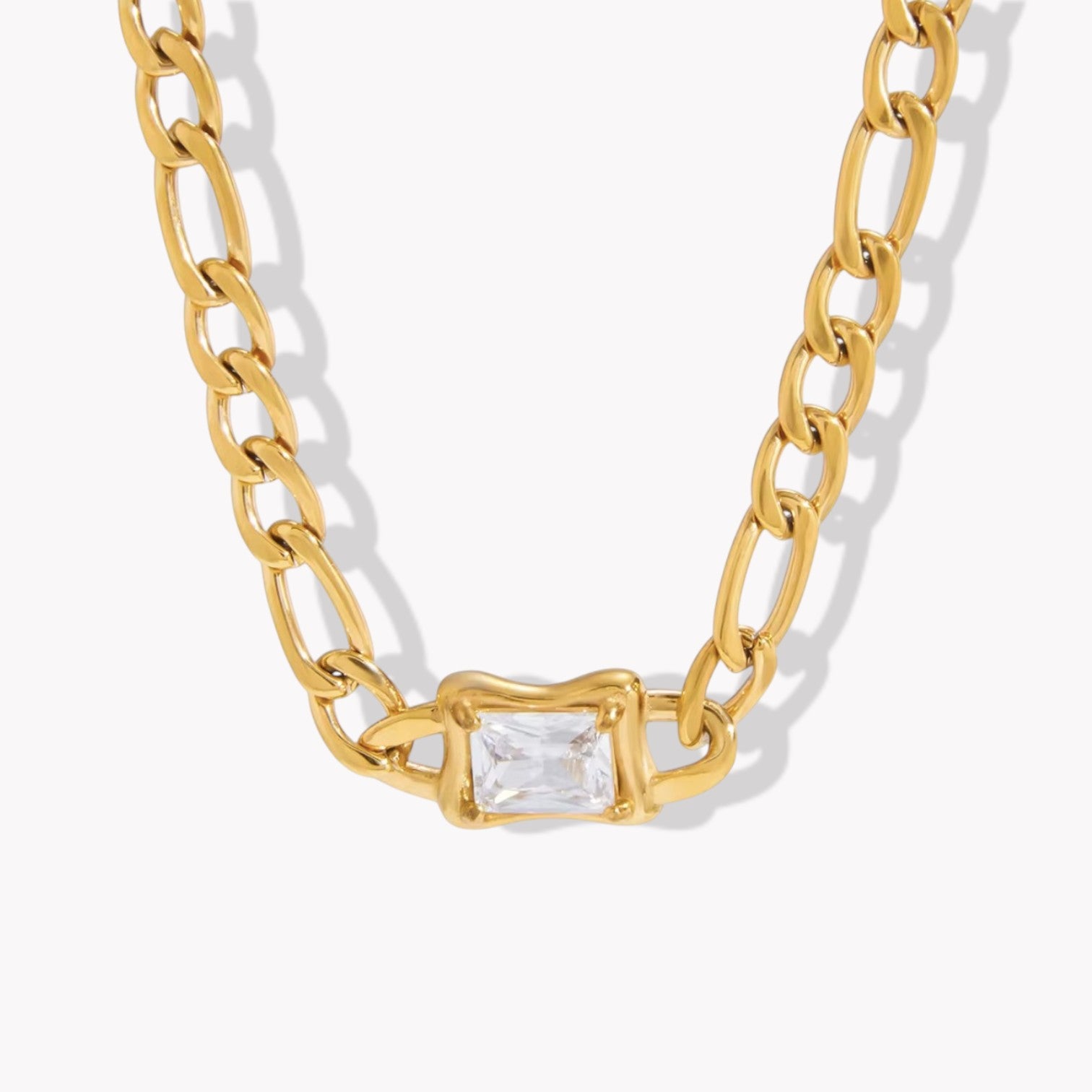 Gold chain necklace with a clear gemstone on a white background
