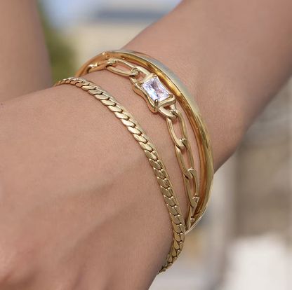 Gold bracelets on a wrist with a blurred background