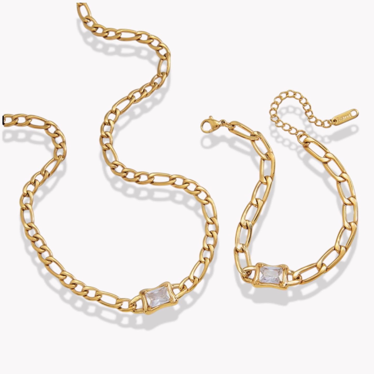 a gold necklace and bracelet pictured on a white background, both with large links and a rectangular gemstone