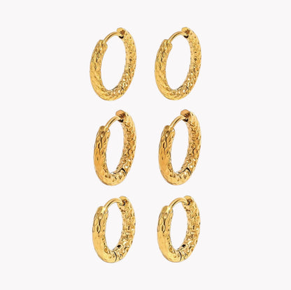 Six pairs of textured gold huggie hoop earrings arranged in a grid on a plain white background.