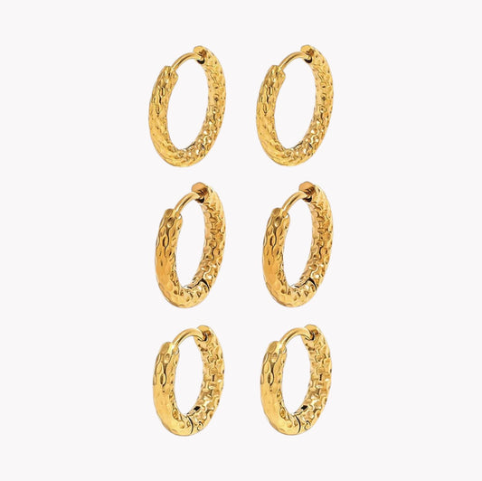Six pairs of textured gold huggie hoop earrings arranged in a grid on a plain white background.