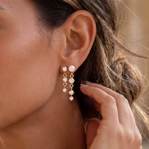 gold earrings with round gemstones pictured being worn
