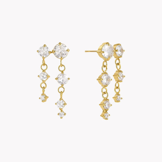 gold earrings with round gemstones pictured on a light grey background