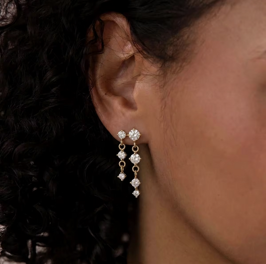 gold earrings with round gemstones pictured being worn