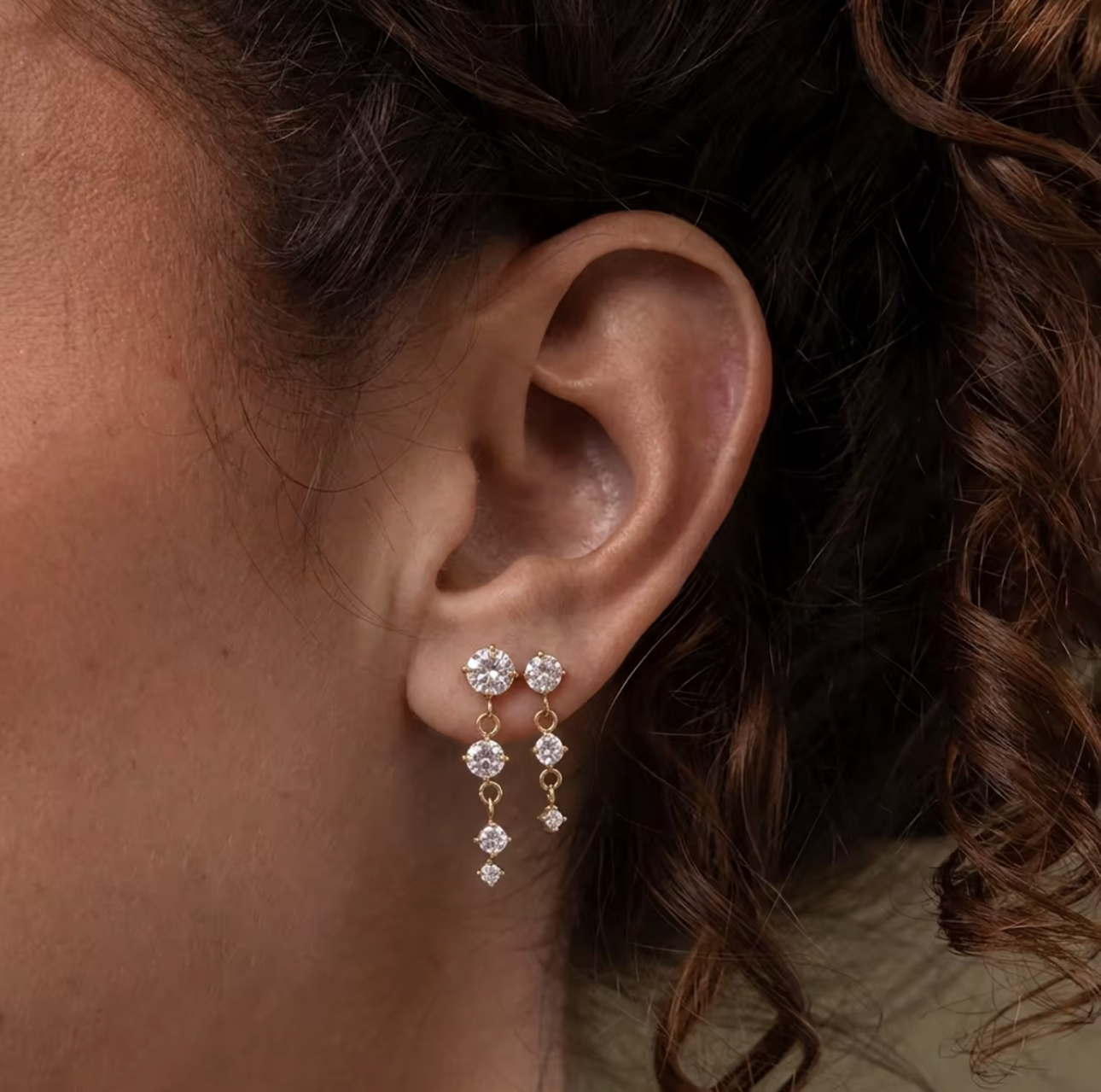 gold earrings with round gemstones pictured being worn