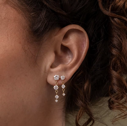 gold earrings with round gemstones pictured being worn