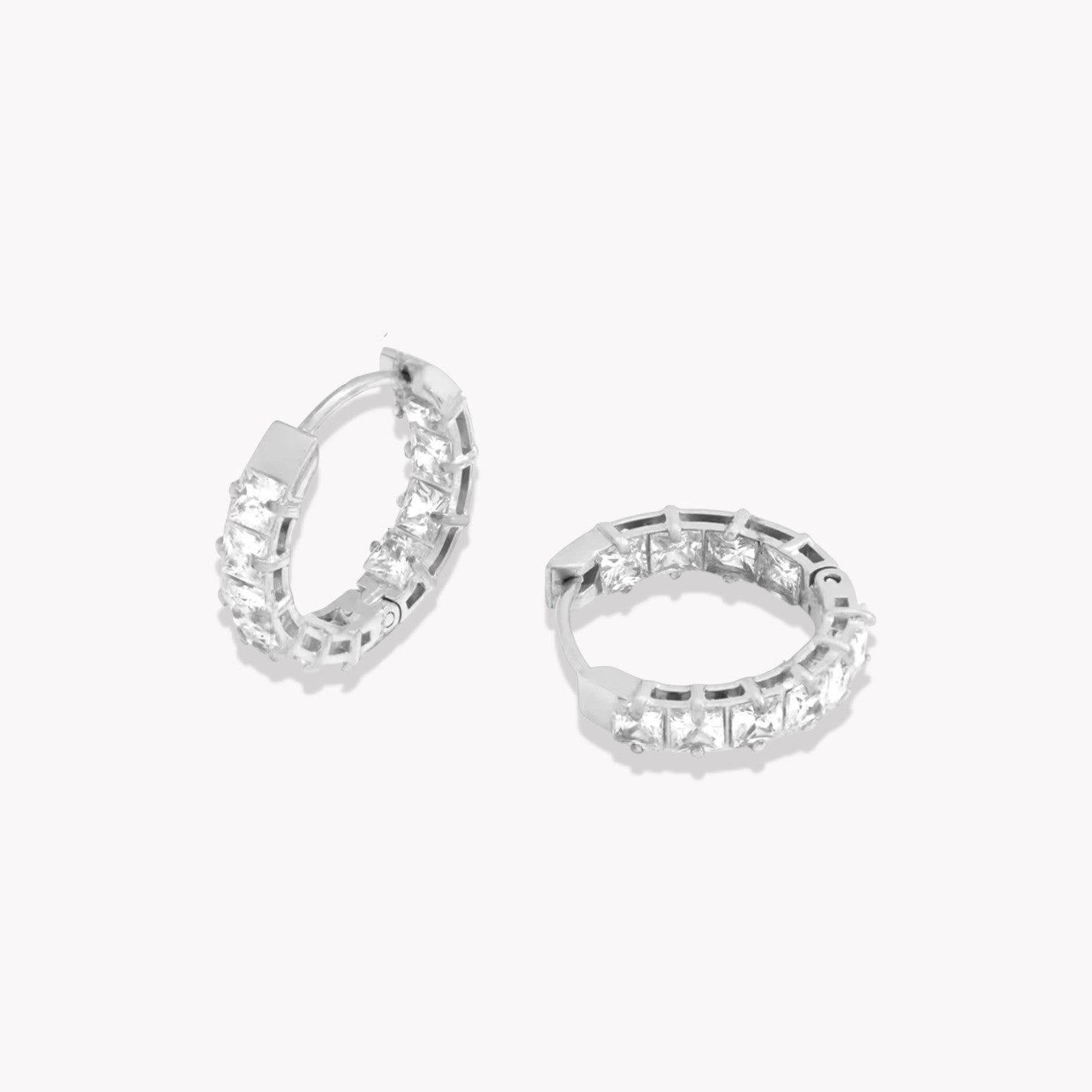 Pair of silver hoop earrings with clear gemstones on a white background