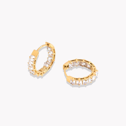 Gold hoops featuring gemstone detail pictured on a light grey background