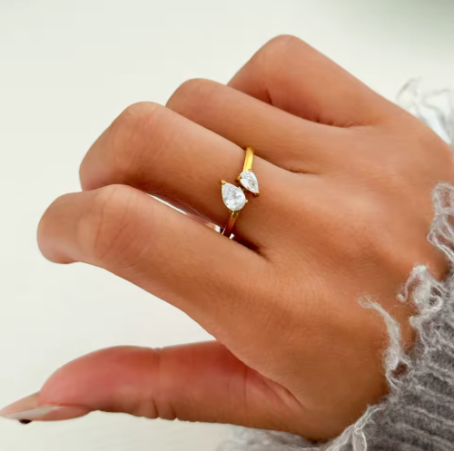 Hand wearing two diamond rings on a neutral background
