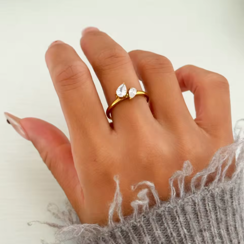 Hand wearing a gold ring with a diamond on a light background