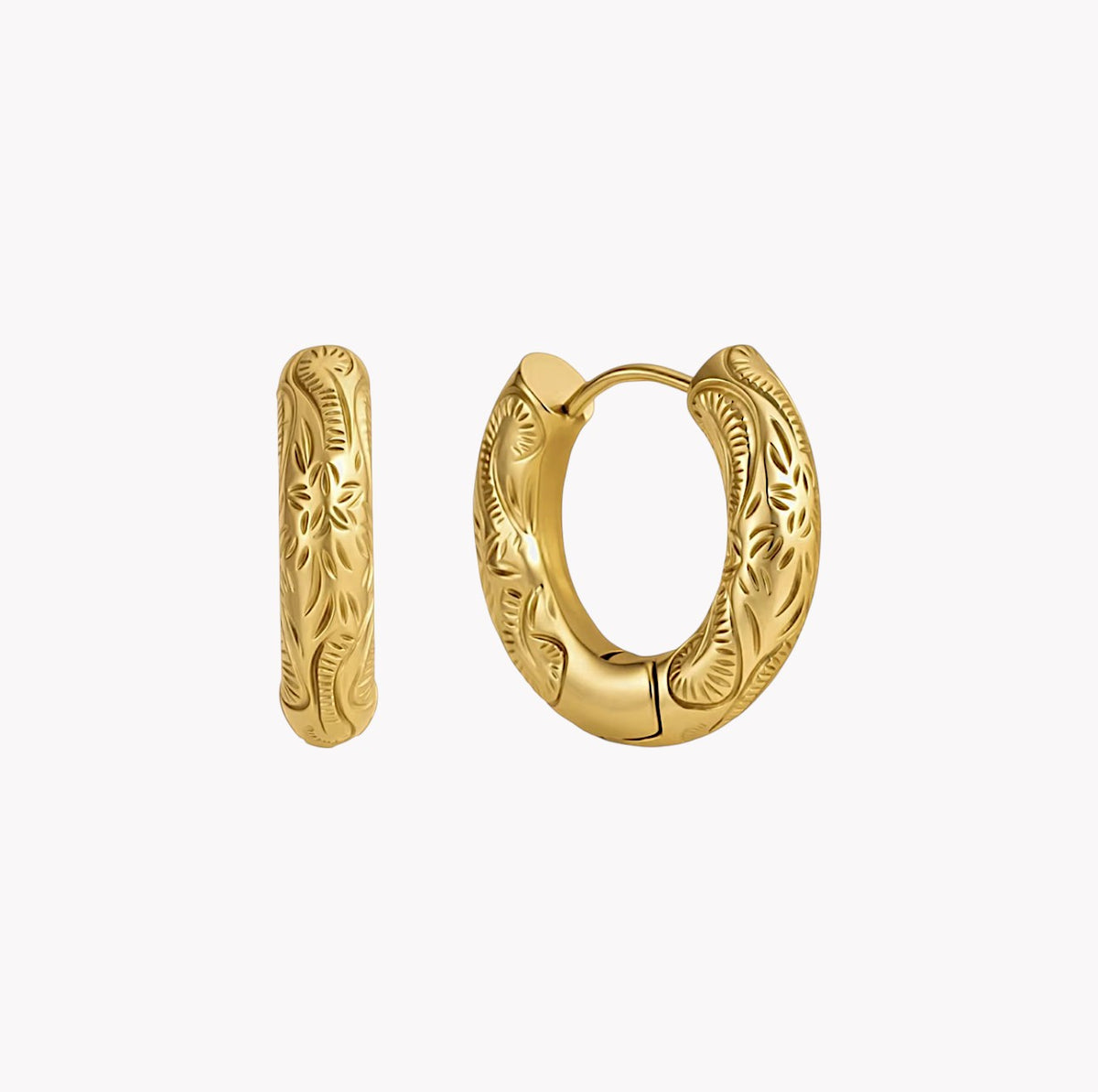 A pair of gold huggie hoop earrings with detailed floral engraving, shown on a clean white background.