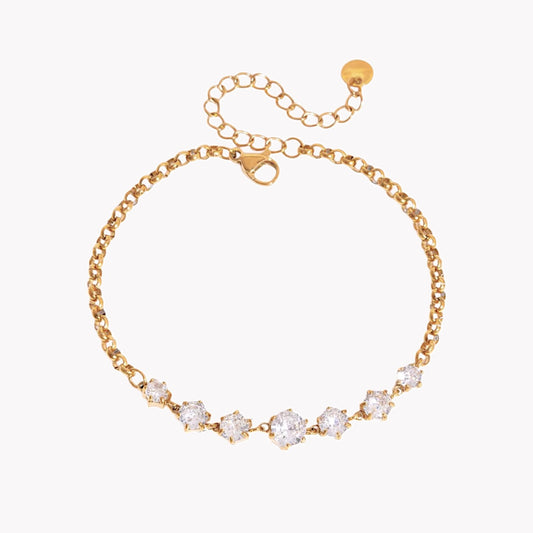 gold bracelet with 7 round gemstones pictured on a light grey background