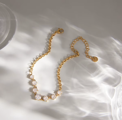 Gold bracelet with clear stones on a white fabric background