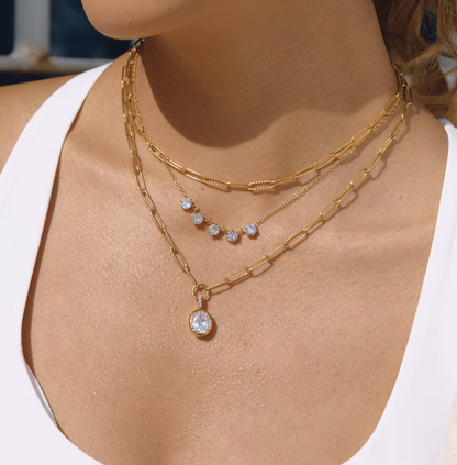 Close-up of a person wearing gold necklaces with diamond pendants.