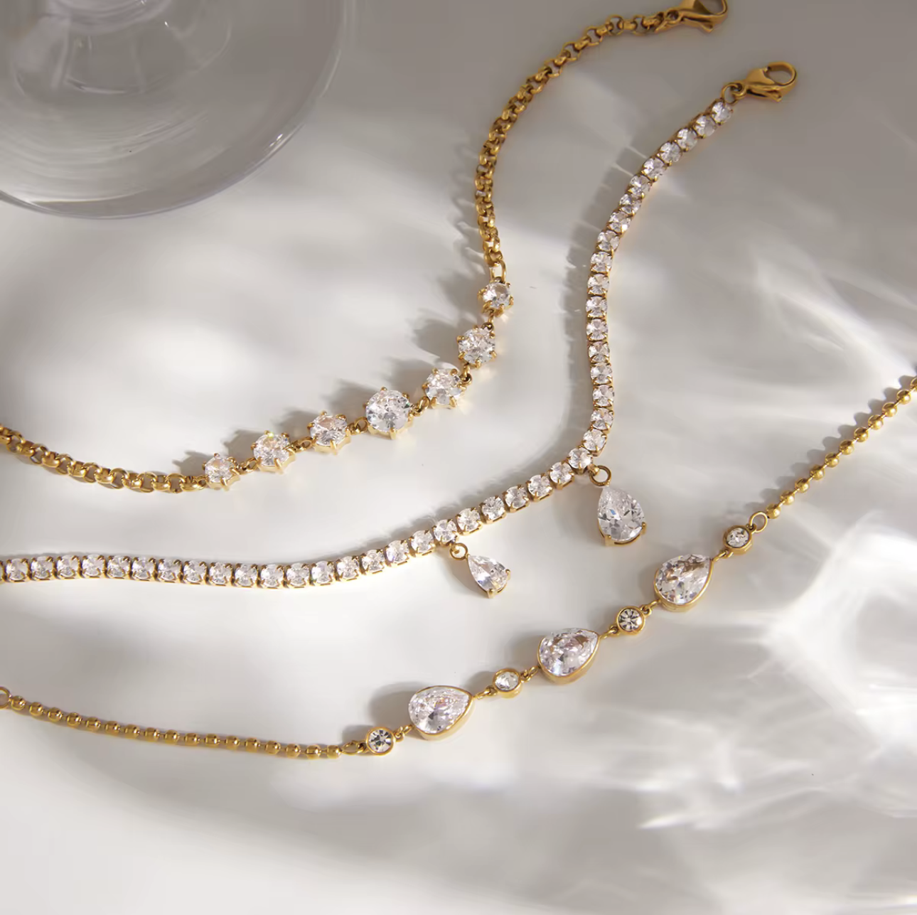 Gold necklaces with crystal-like stones on a white surface