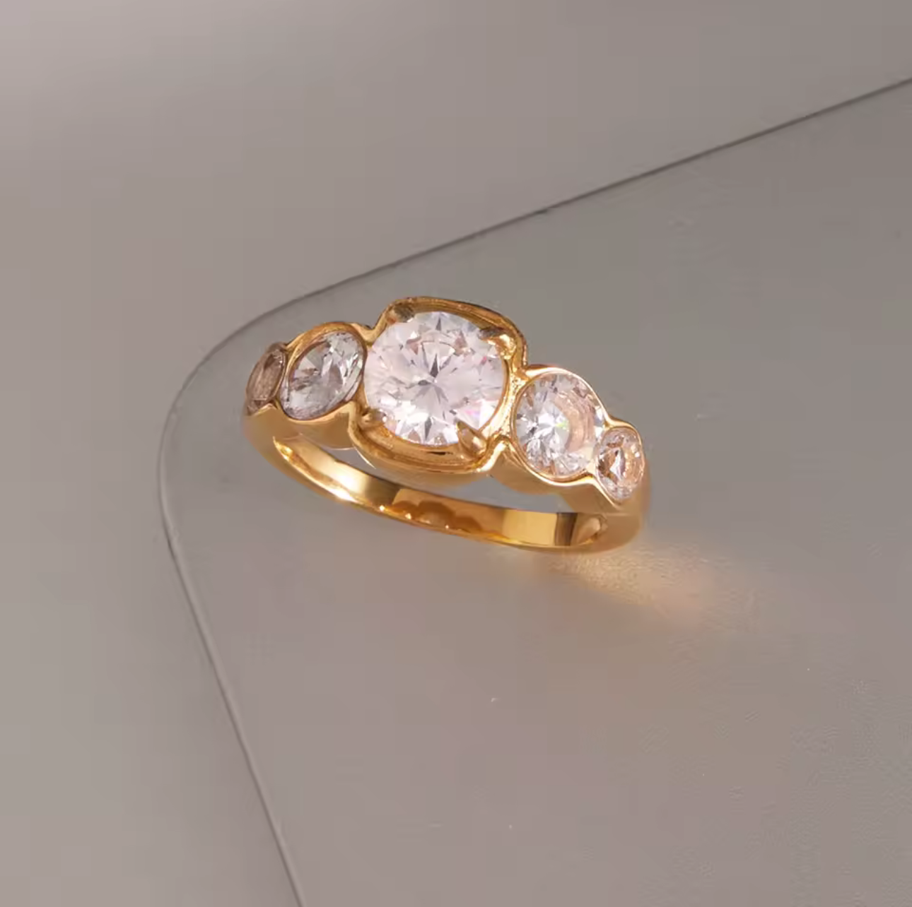 Gold ring with five diamonds on a reflective surface