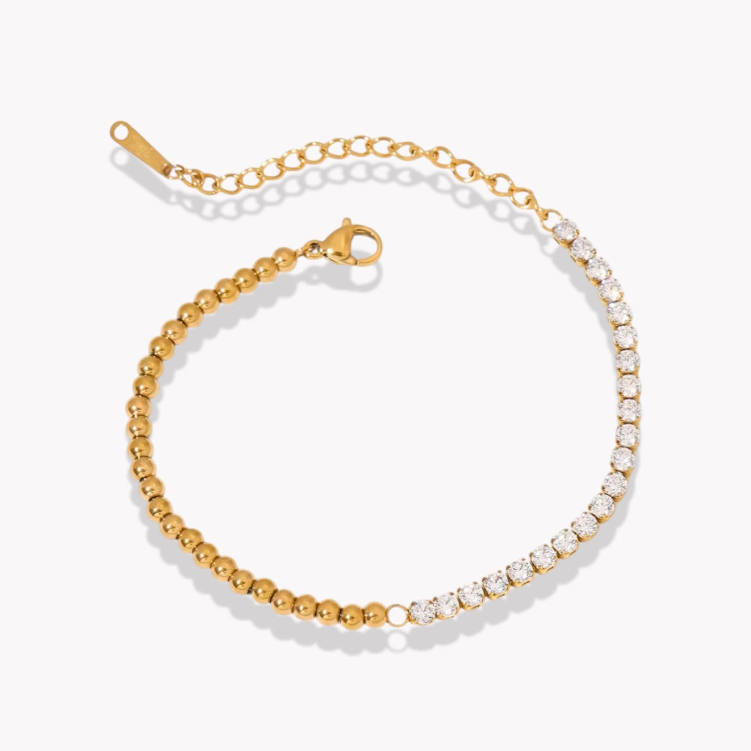 gold bracelet with half bead detail and half crystal tennis detail on a light background