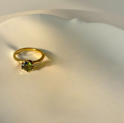 Gold ring with a green gemstone on a white background