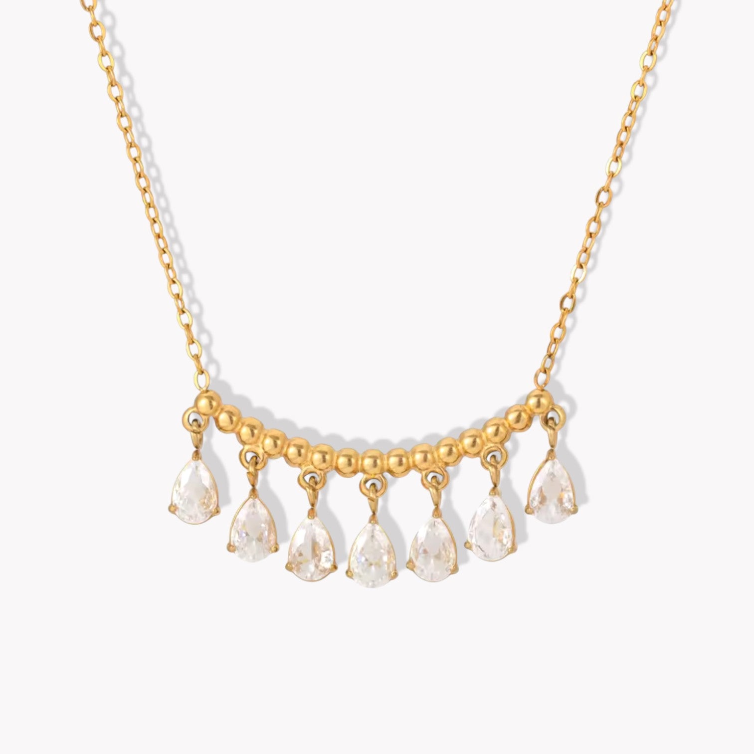 gold necklace featuring a row of pear shaped gemstones pictured on a white background