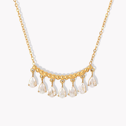 gold necklace featuring a row of pear shaped gemstones pictured on a white background