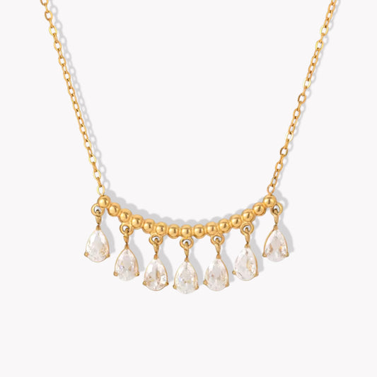 gold necklace featuring a row of pear shaped gemstones pictured on a white background