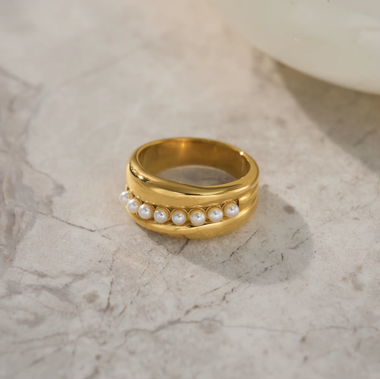 Gold ring with pearls on a marble surface