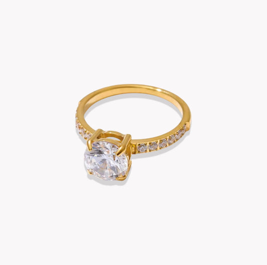 Gold ring with a clear gemstone on a white background
