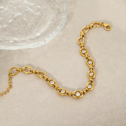Gold bracelet with embedded stones on a beige surface
