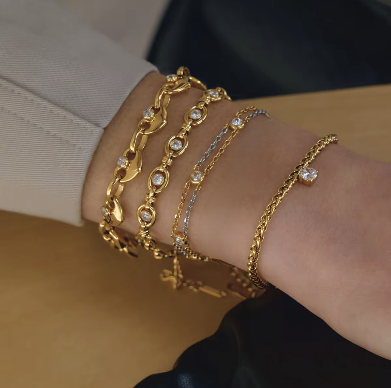 5 gold bracelets being worn on a wrist
