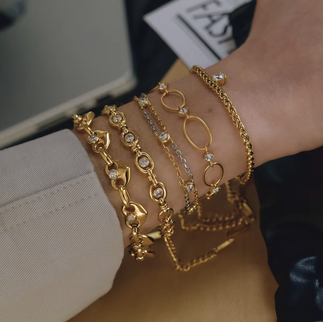 5 gold bracelets being worn on a wrist