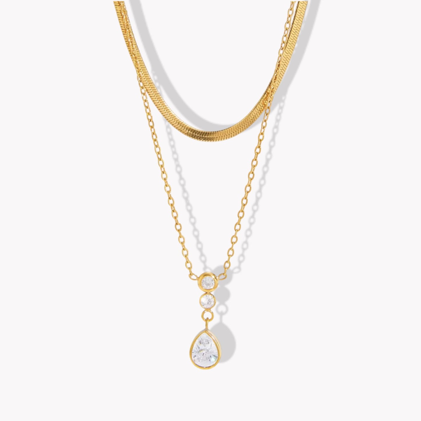 Double layer necklace featuring a top layer snake chain with bottom longer layer with pear shaped gemstone pendant pictured on a light background