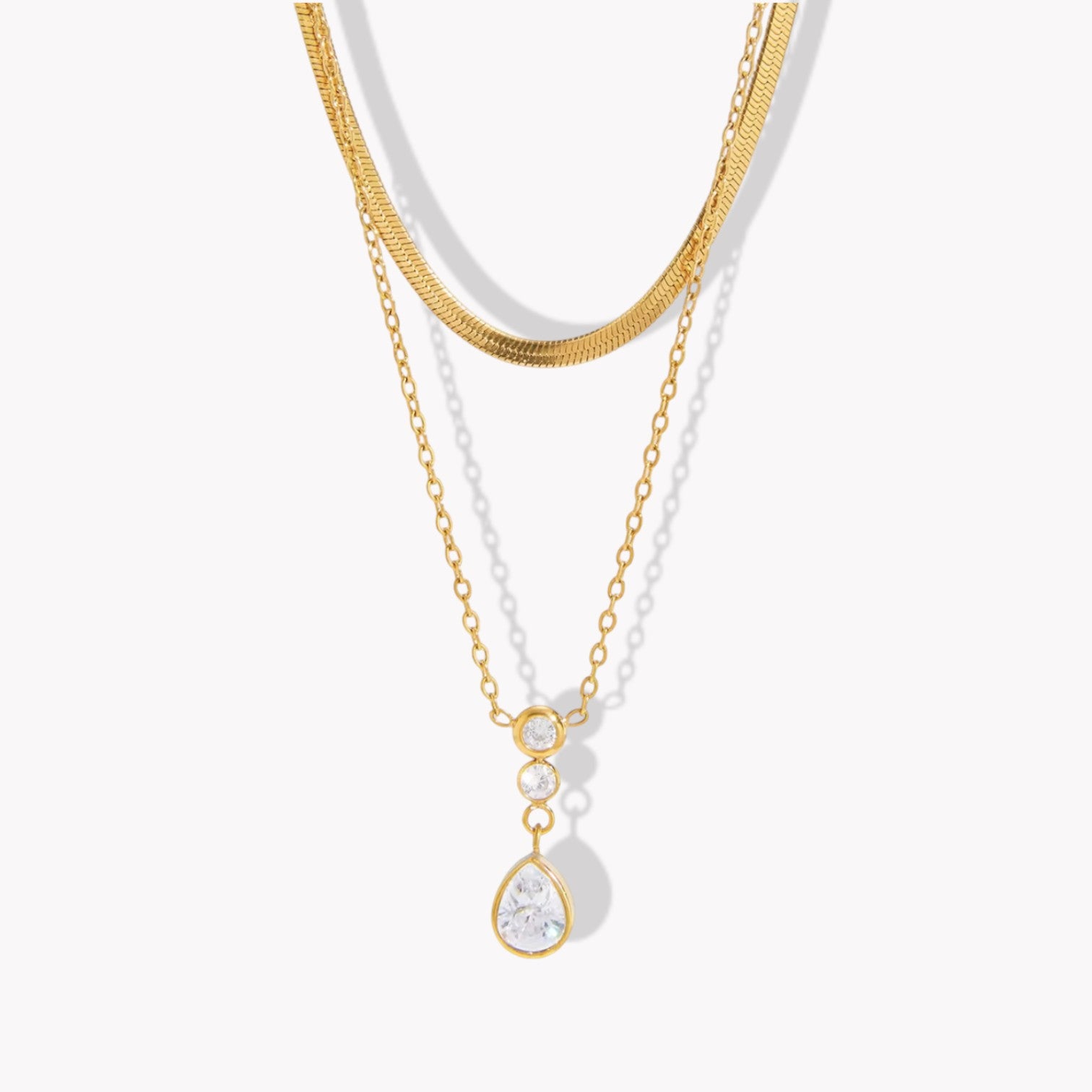 Double layer necklace featuring a top layer snake chain with bottom longer layer with pear shaped gemstone pendant pictured on a light background